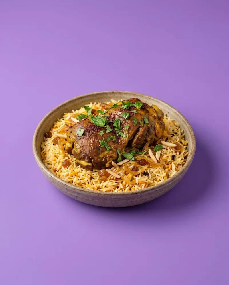 Kip biryani met kruidige rijst, rozijnen en amandelen op een paarse achtergrond